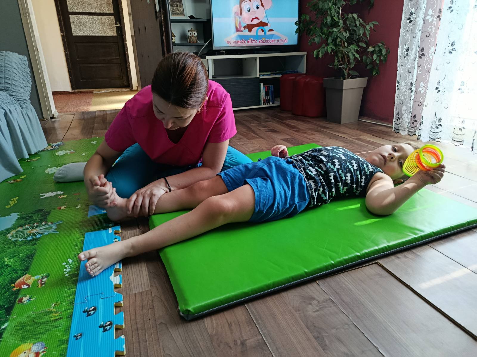 Fizioterapeut radi vežbe pokretljivosti sa detetom u njegovom domu